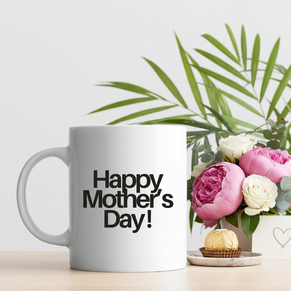 White ceramic coffee mug with 'Happy Mother's Day!' design on a table with a plant